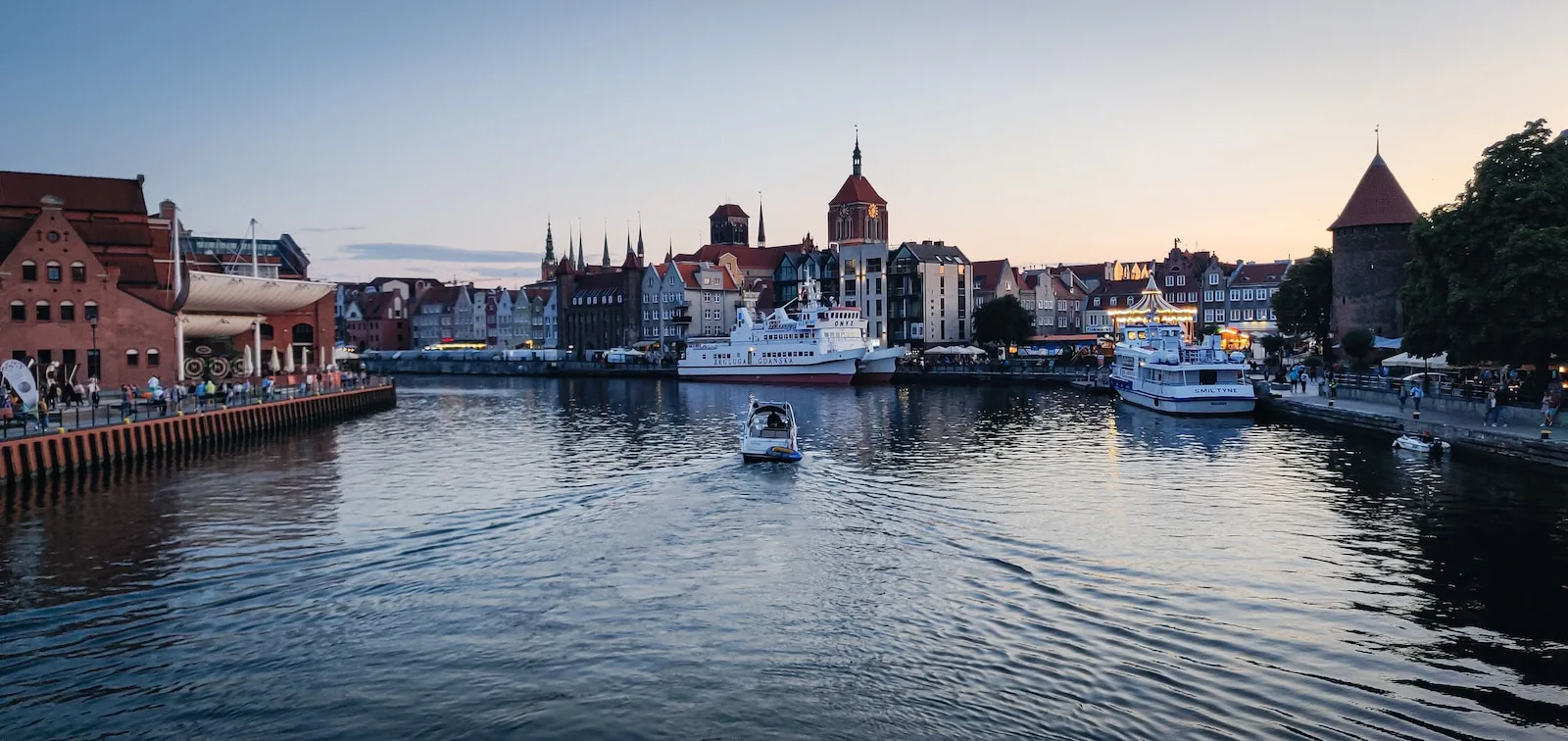 white and brown boat on water near city buildings during daytime